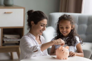 Mother and daughter saving in piggy bank